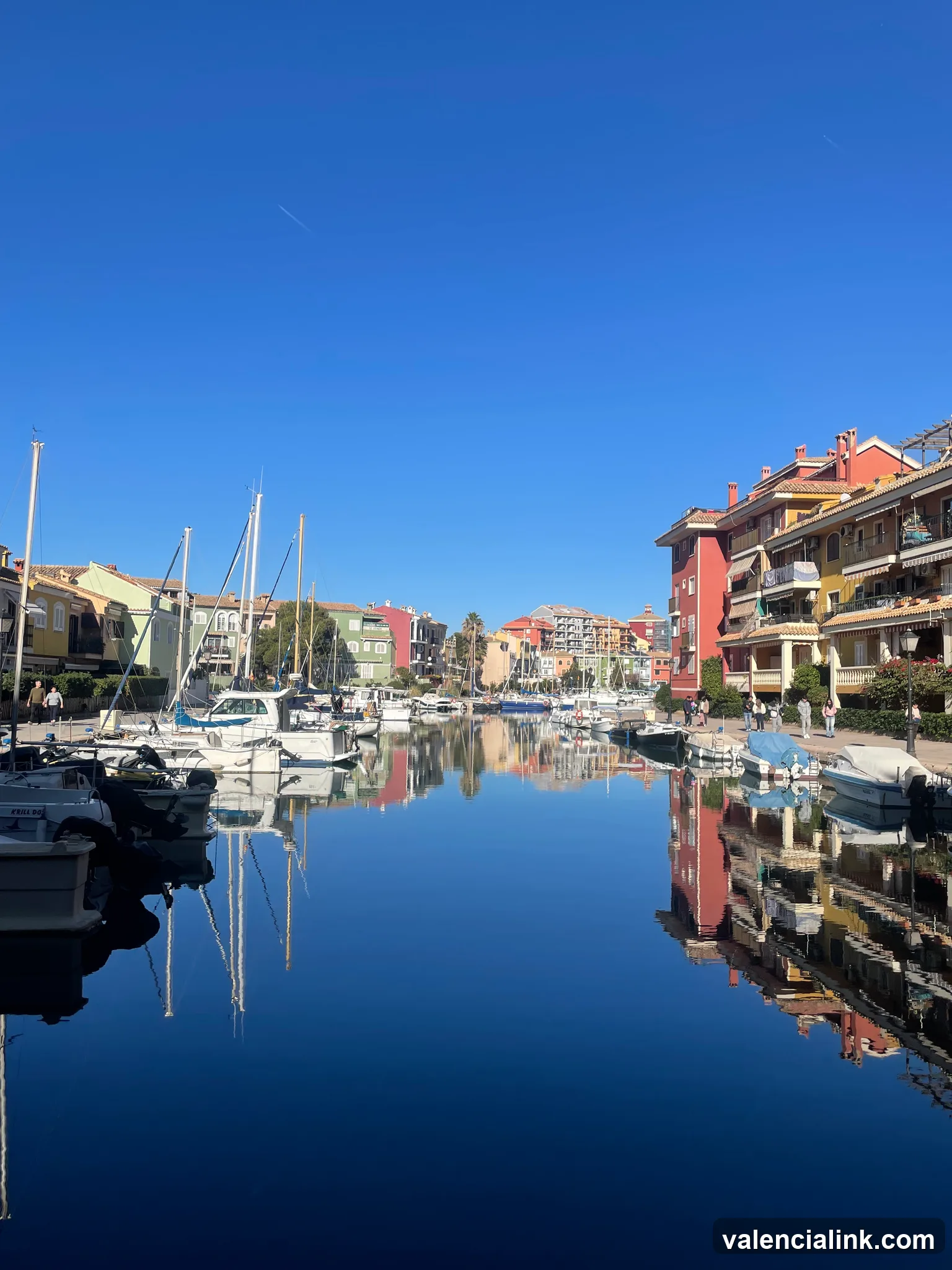 A tranquil marina with colorful buildings and boats under a clear blue sky.