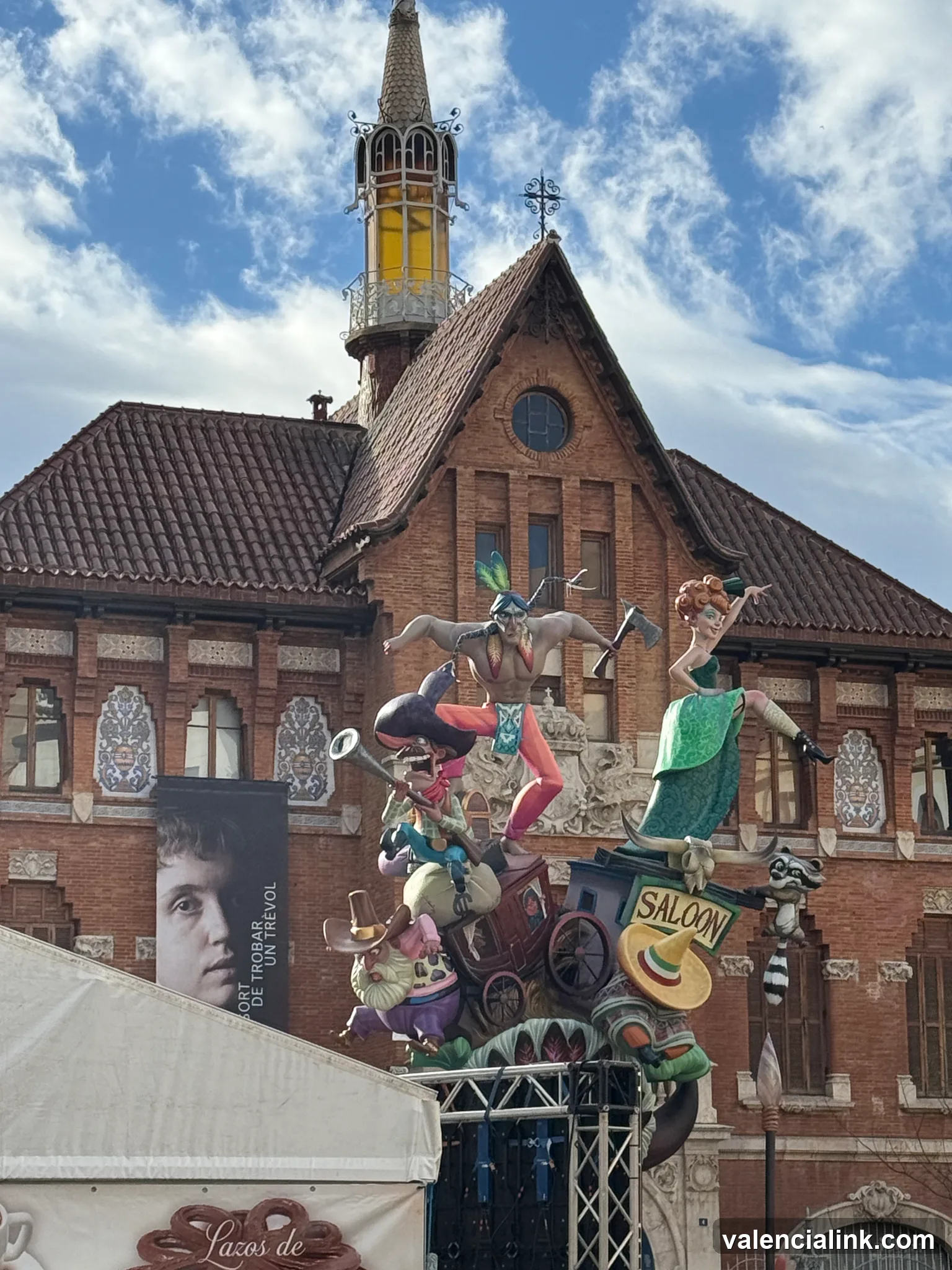 A festive float with figures and a 'Saloon' sign in front of a brick building with a spire.