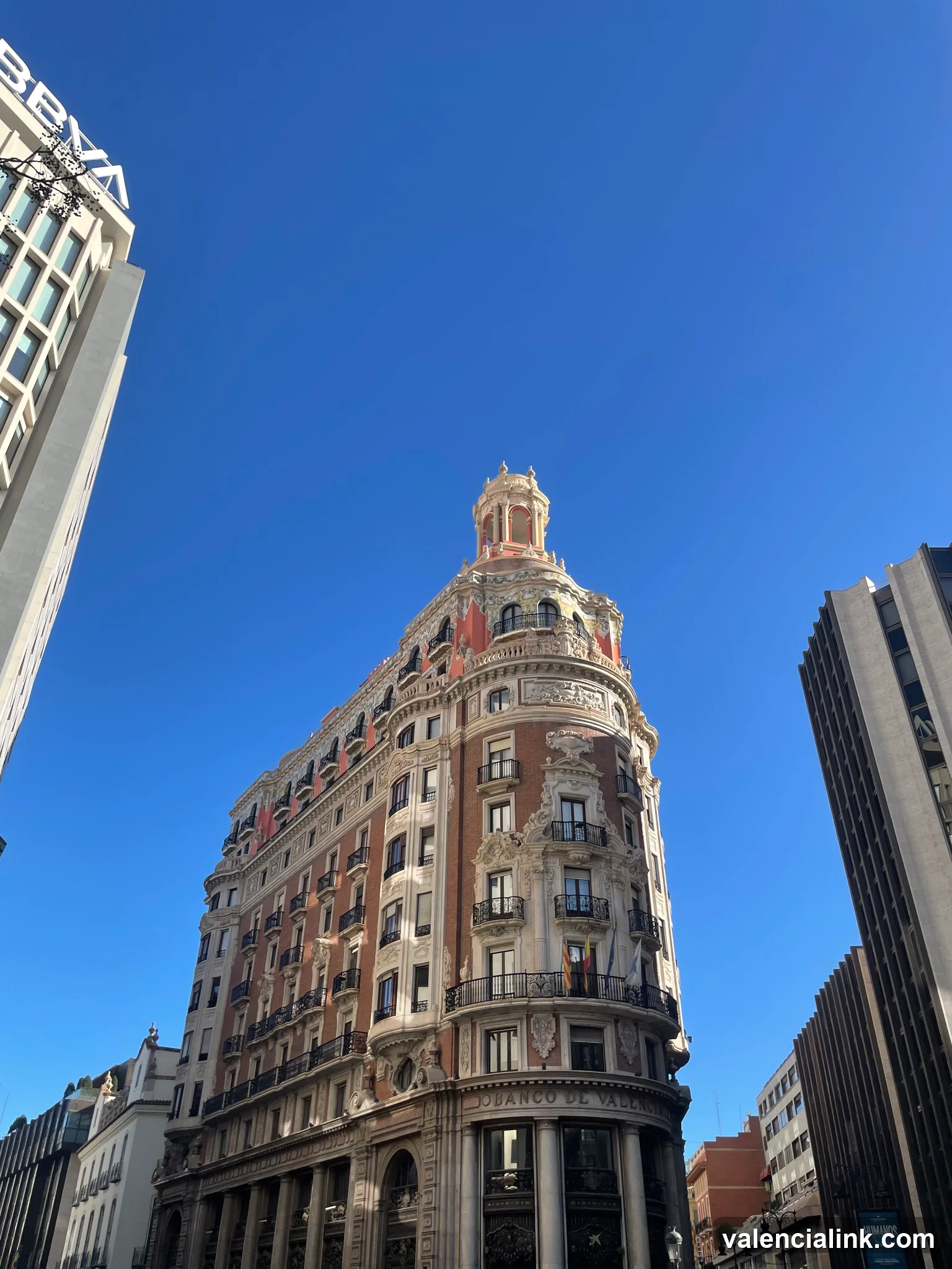 Tall ornate building with spire against clear blue sky.