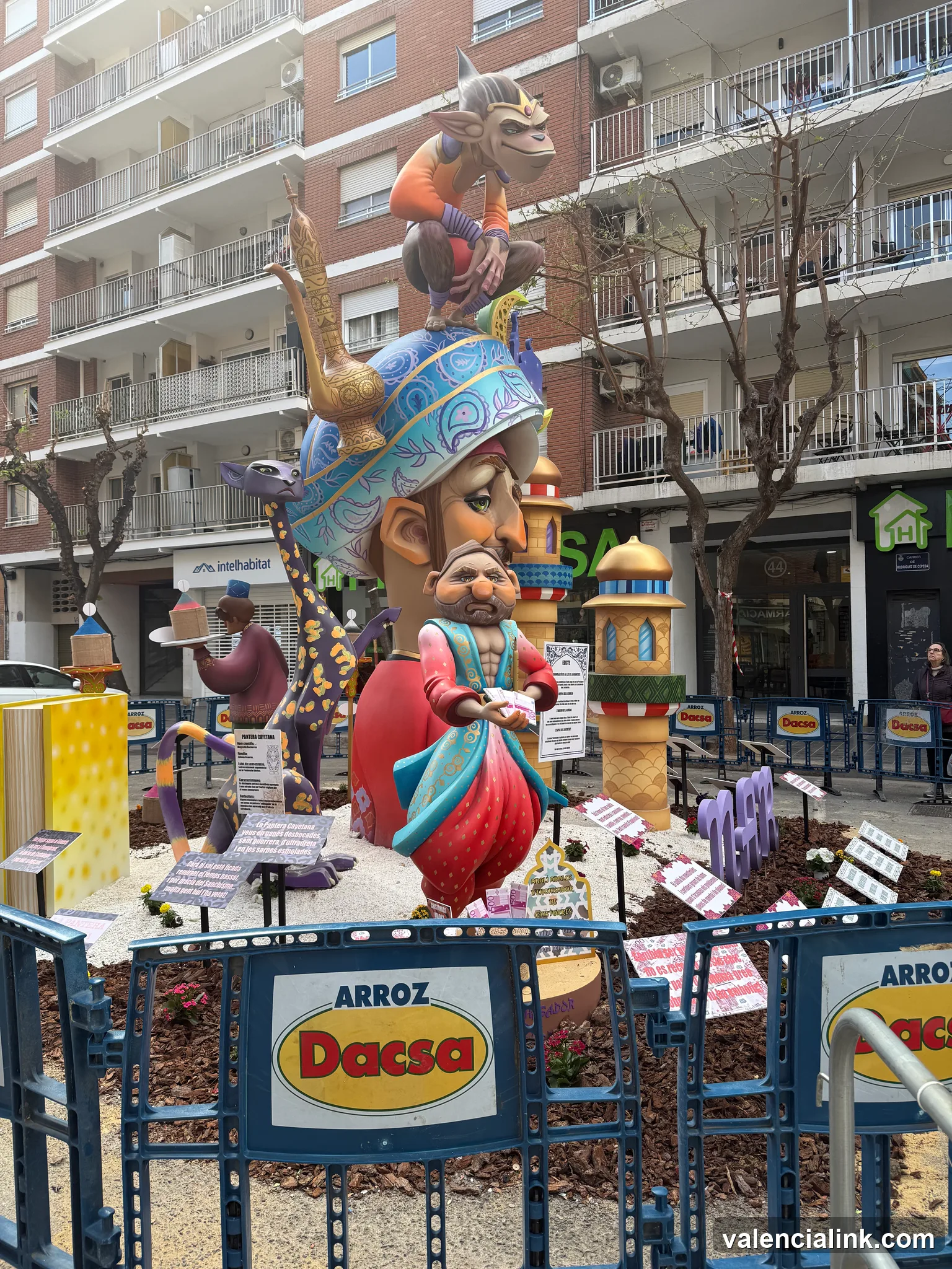 A vibrant float with figures and 'Arroz Dacsa' signage in front of a residential building.