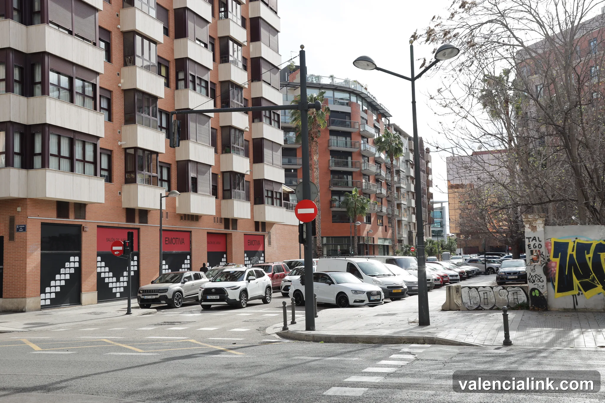 Modern urban street with parked cars and residential buildings.