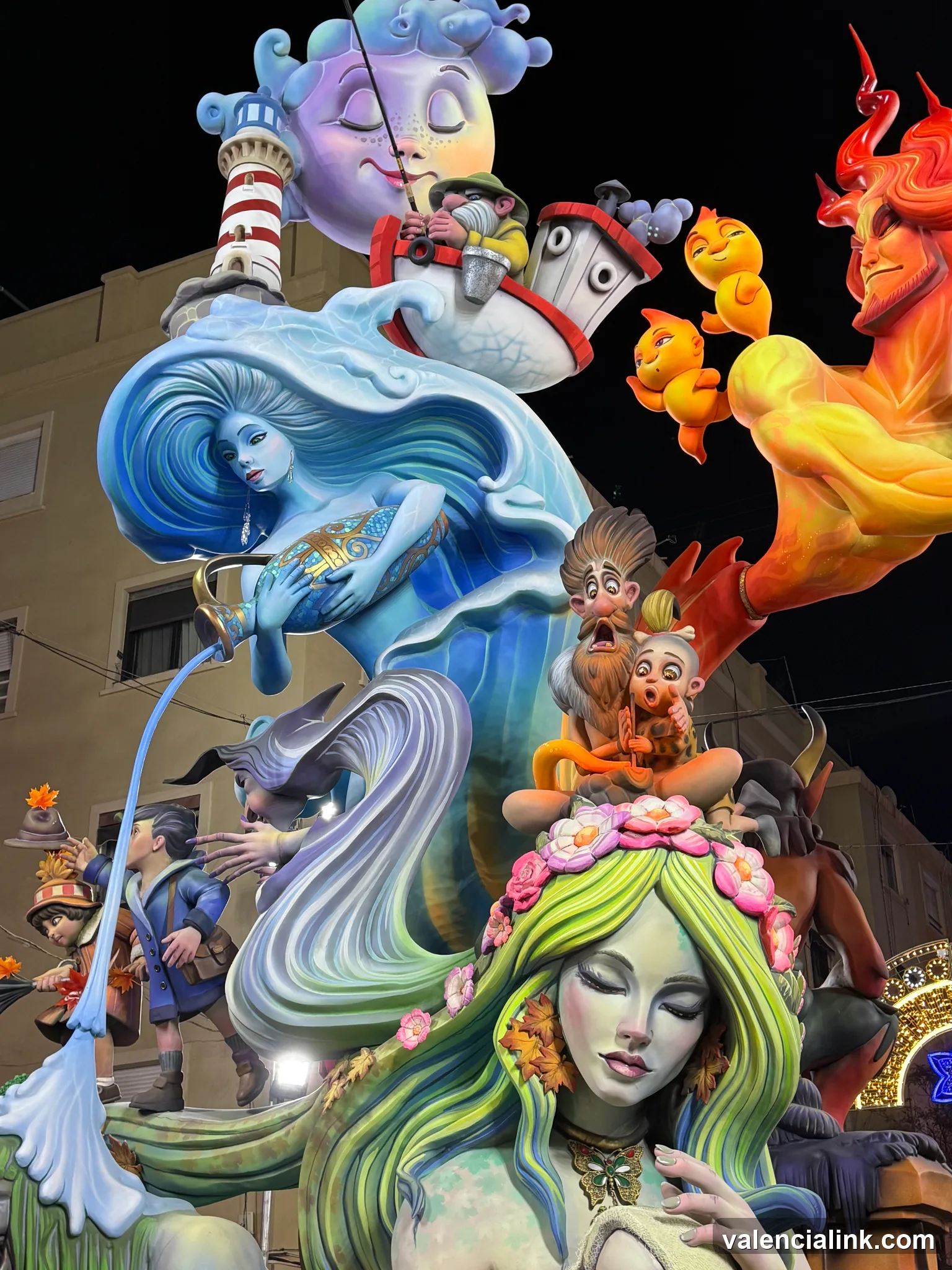 A vibrant float with mermaid and devil figures at night.
