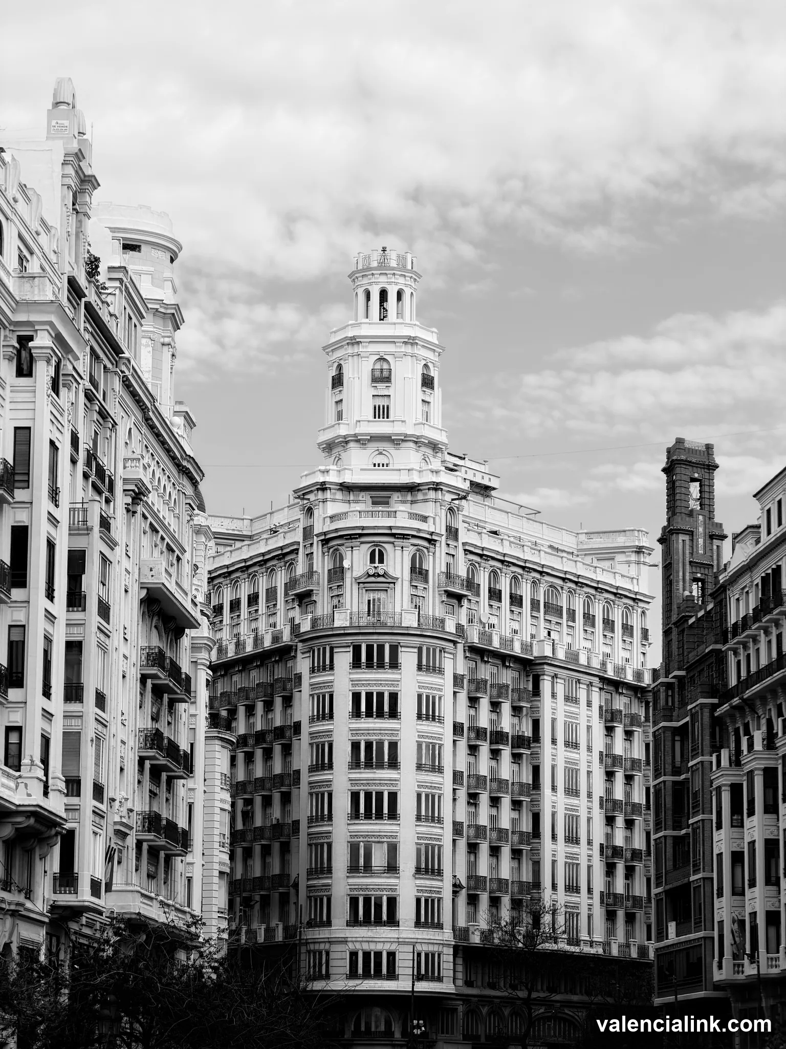 Tall, ornate black and white building with curved facade and multiple windows.