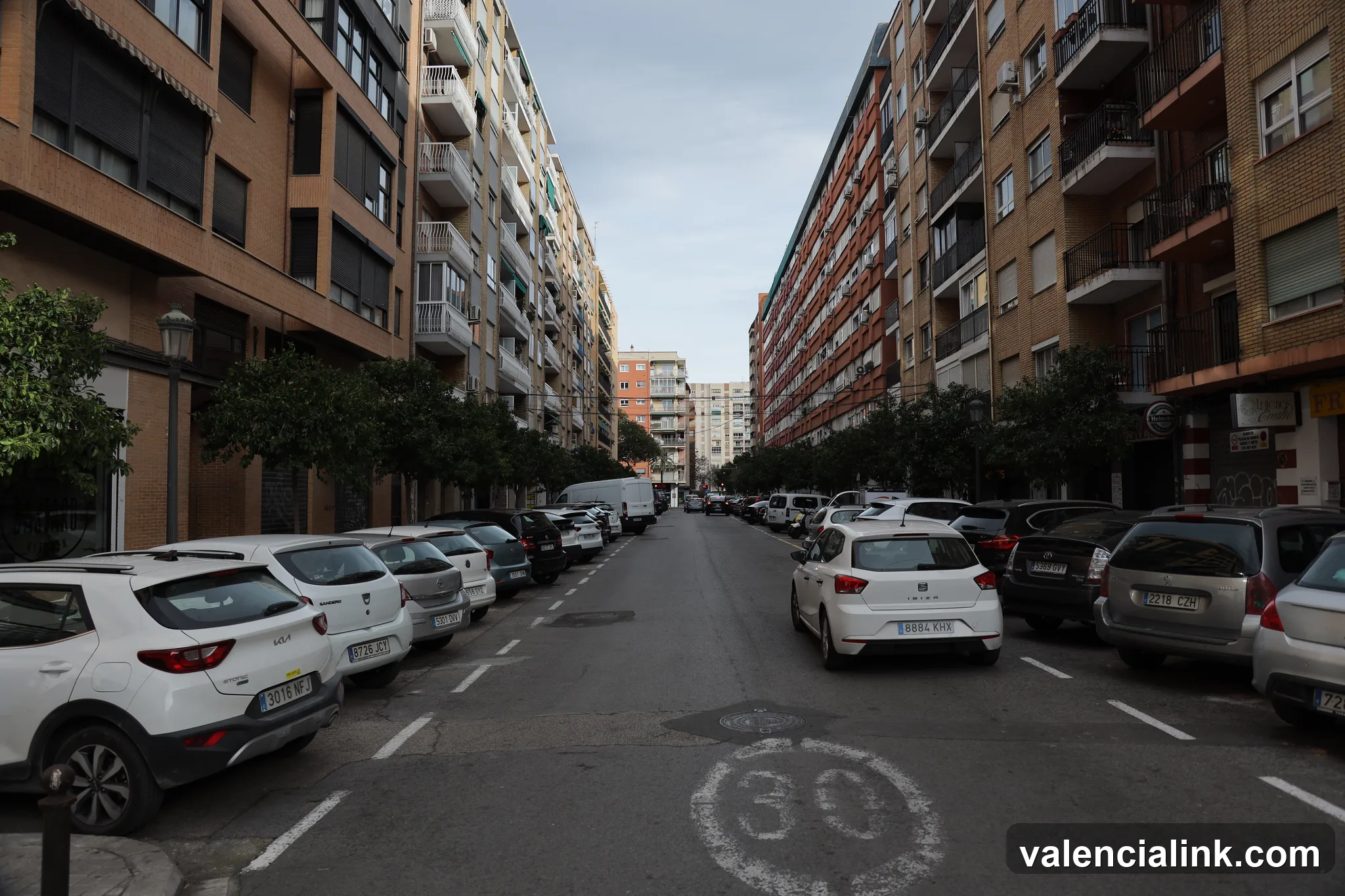 Una escena de calle con coches aparcados y edificios de apartamentos.