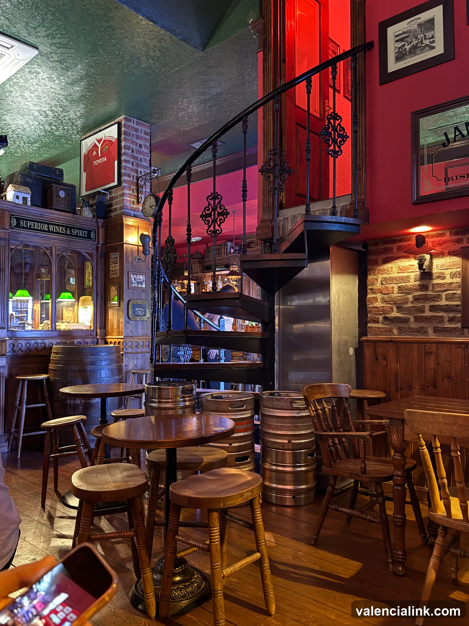 Intérieur d'un pub rustique avec des meubles en bois et un escalier en colimaçon.