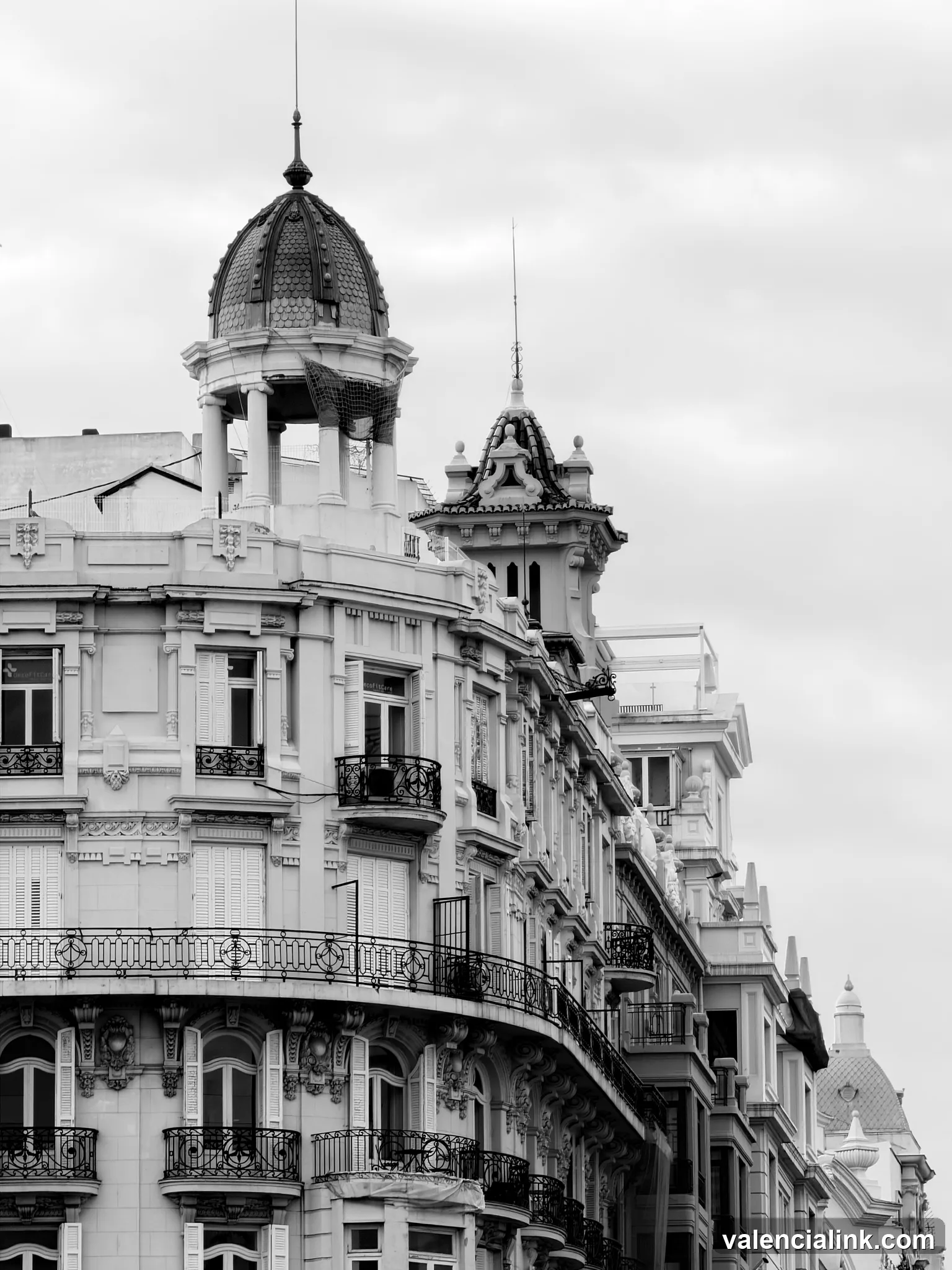 Black and white image of ornate buildings with balconies and decorative architecture.